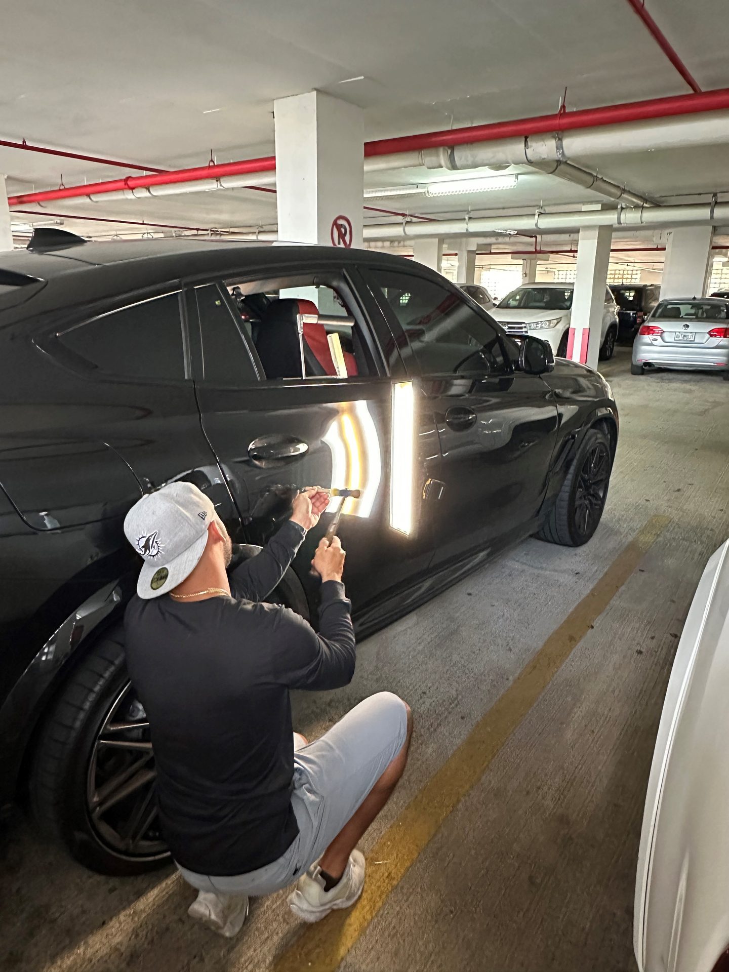 Brandon, owner and lead technician of Caliber PDR, performing paintless dent repair in Miami