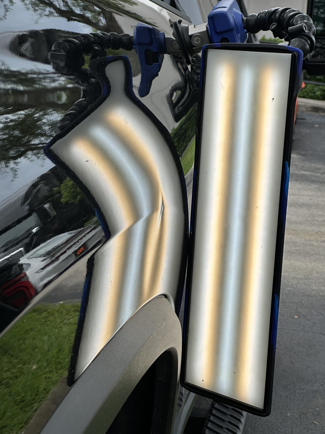 Dent on a black panel shown under a PDR reflection board, Miami