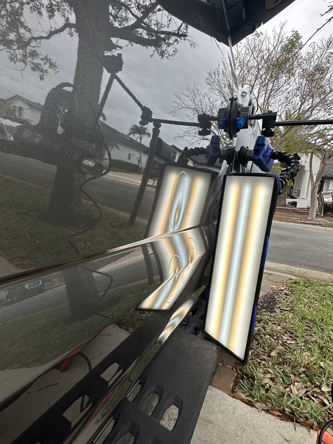 Dent on a black hood shown under a PDR reflection board, Miami