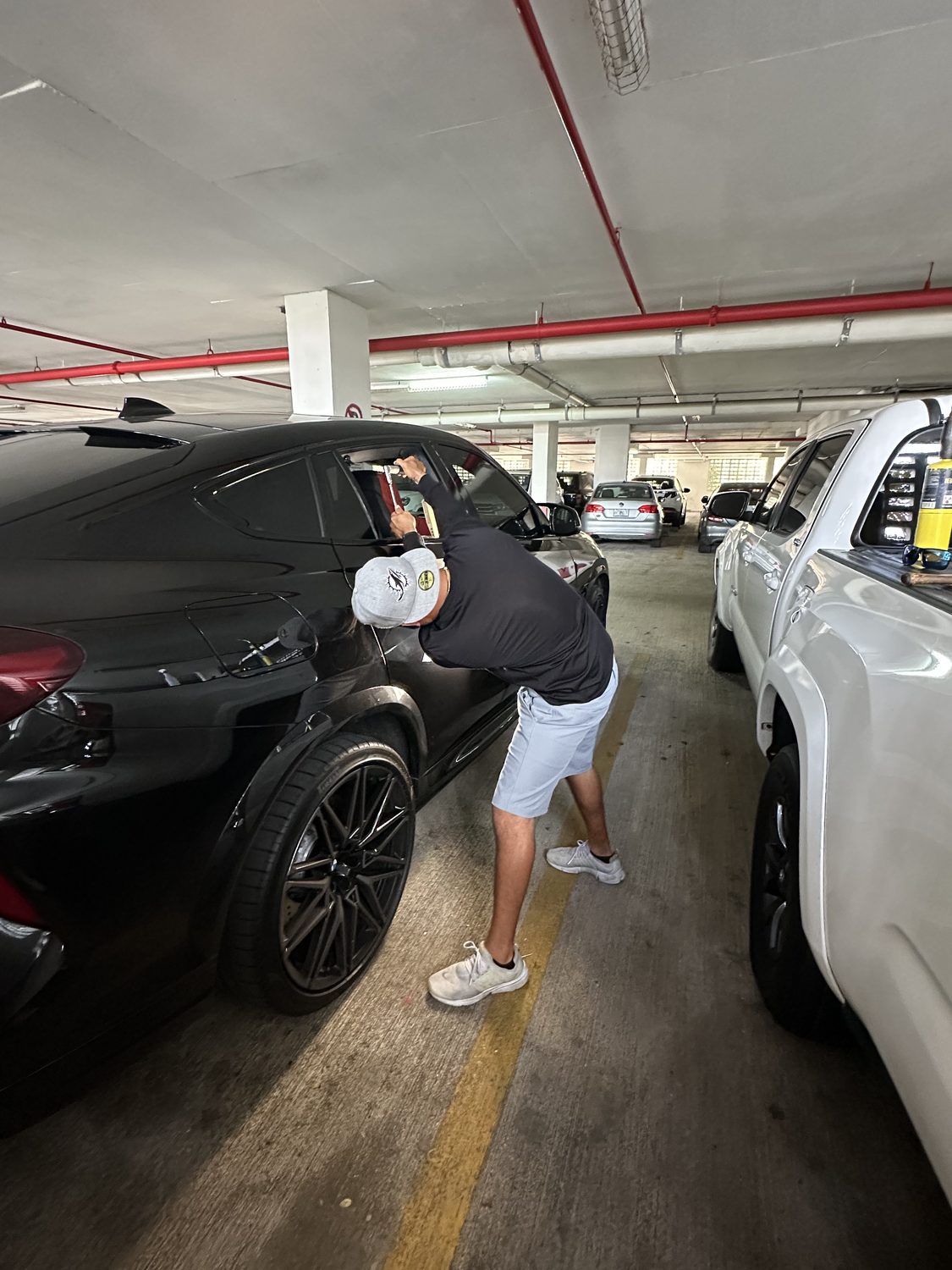 Technician performing paintless dent repair on a black car, Miami